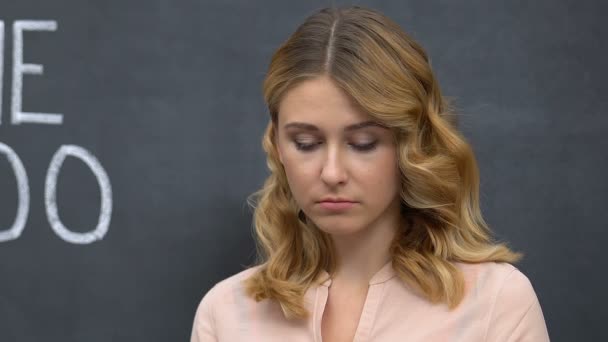 Расстроенная женщина, стоящая рядом с хэштегом MeToo на доске, прекращающая домогательства, оскорбления — стоковое видео