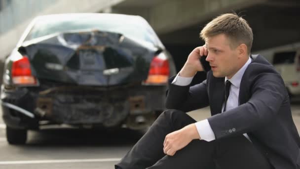 Hombre frustrado sentado en la carretera, llamando a la policía después de un accidente de tráfico, accidente de coche — Vídeo de stock