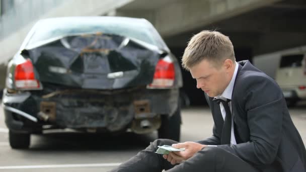 Hombre contando euros, mirando daños coche después de accidente de tráfico, reparaciones costo — Vídeo de stock