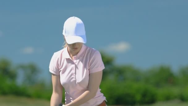 Mädchen macht halben Schwung und schlägt Golfball, macht ja Geste, guter Versuch — Stockvideo