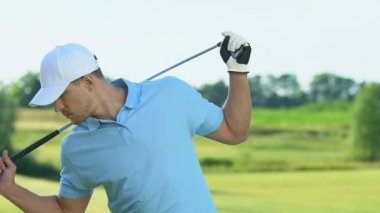 Kendine güvenen golf oyuncusu topa vurmadan önce geri ve omuz kaslarını ısıtıyor