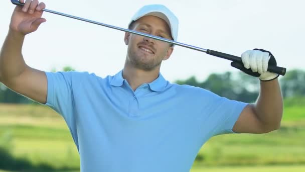 Schöner Golfer in professioneller Uniform, der mit Schläger in die Kamera lächelt — Stockvideo