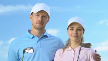 Kendine güvenen erkek ve kadın golfçüler kulüpleri ile poz, golf okulu eğitmenleri