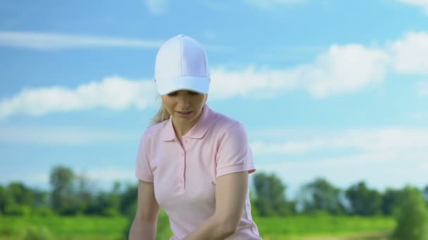 Молодая женщина тренируется играть в гольф на поле в солнечный день, счастлив с хорошим хитом — стоковое видео