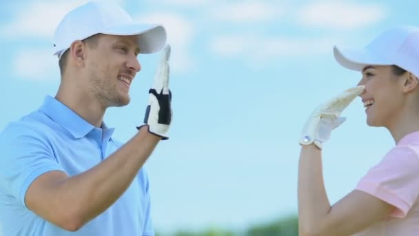 Leende man och kvinna i Golf Uniform ger hög fem, flirta efter träningen — Stockvideo