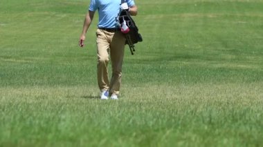 Kendine güvenen golf oyuncusu golf çantası ile fairway boyunca yürüyüş, onun oyun bitirme