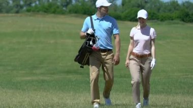 Genç çift golf sahasında bir sonraki deliğe yürüyor, golf çantası taşıyan adam, hobi
