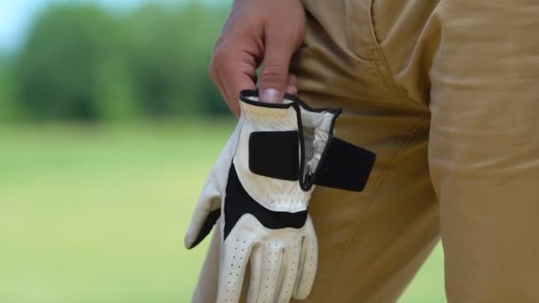 Мужчина надевает и закрепляет на руке профессиональную кожаную перчатку, игру в гольф, хобби — стоковое видео
