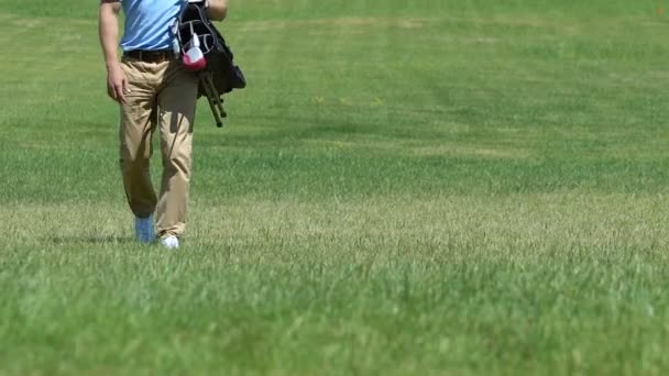 Homem com saco de golfe andando ao longo fairway para o próximo buraco, mudando de local, hobby — Vídeo de Stock