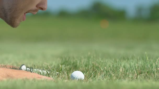 Hombre soplando pelota de golf en el agujero y regocijo, rompiendo reglas, broma, primer plano — Vídeo de stock