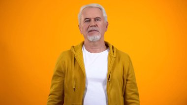 Kendine güvenen modern üst düzey adam kamera, sarı arka plan, yaşam tarzı bakıyor