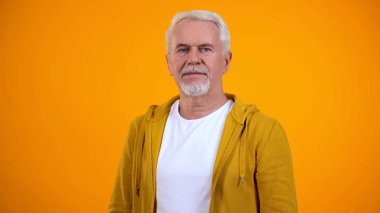 Gülümseyen modern üst düzey adam kamera bakıyor, sarı arka plan, reklam izole