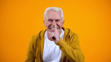 Turuncu arka plan üzerinde bilim jest gösteren neşeli yaşlı adam, indirimler