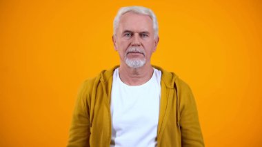 Pensive emekli kamera bakıyor, sarı arka plan, sorun izole