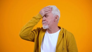 Gri saçlı emekli turuncu arka plan karşı yüz-palmiye jest gösteren, başarısız