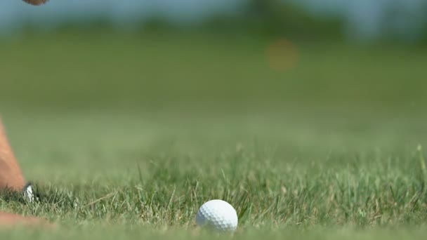 Mužský golfový hráč, který se baví na trávě a fouká do díry, zblízka — Stock video