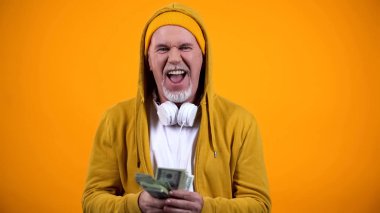 Dolar notaları tutan ve müzik dinleyen şık giysiler neşeli yaşlı dj