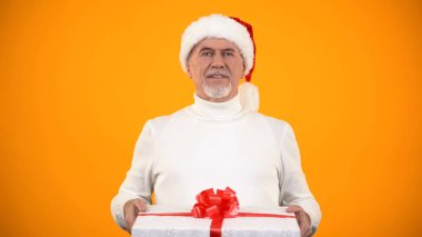 Santa şapka hediye kutusu tutan Pozitif yaşlı adam, en iyi mağaza reklam sunar