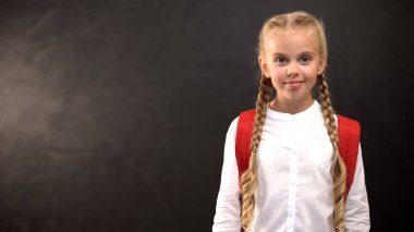Sırt çantası ile Schoolgirl tahtaya karşı kamera gülümseyen, istatistik şablonu