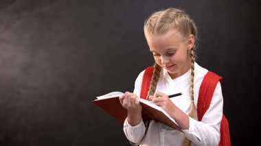 Rüya gibi küçük kız öğrenci not defterine yazıyor, tahtaya karşı ödev yapıyor