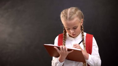 Ciddi kız öğrenci not defterine yazma, konsantre yüz, görev ile toplamları yapıyor