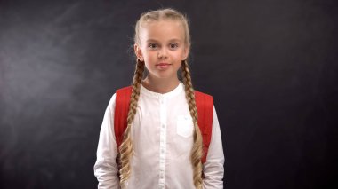 Pretty ilkokul öğrencisi tahta arka plan karşı kamera bakıyor