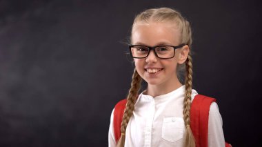 Gülümseyen kız kameraya bakıyor, okula geri döndüğü için mutlu, eğitim