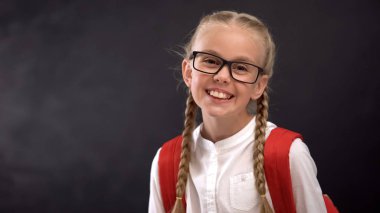 Kamerada gülümseyen gözlükakıllı kız öğrenci, bilgi eğitimi için susuzluk