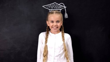 Tahtaya boyanmış akademik şapkalı gülümseyen kız, okul eğitimi