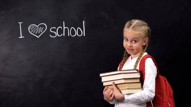 Tahtanın yanında duran kitapları olan yaramaz kız öğrenci, okul deyimini seviyorum.