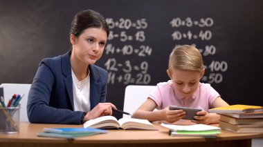Sıkı öğretmen ona öğretmek için akıllı telefon üzerinde oynarken bitirme yaramaz çocuk bekliyor