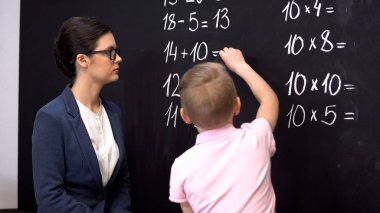 Matematik öğretmeni tahtaya yazma alıştırmaları çözme çalışmalarını kontrol