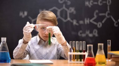 Akıllı öğrenci yeşil reaktif, kimya ile tüp içine ajan damlaları ekleyerek