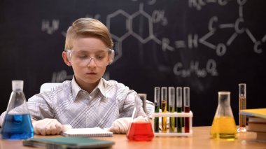 Kimyager çocuk deneyler hakkında düşünen sıvılar ile şişeleri bakarak