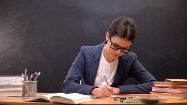 Doğru kadın öğretmen okul sınıfında oturan çocukların ödevlerini kontrol ediyor