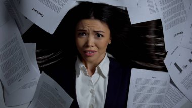 Kameradehşeti ile bakan kadın, kağıt yığını arasında yatan, stresli iş