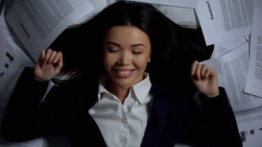 Belgeler arasında yatakta yatan iş kadını, başarılı sözleşme, bitirmek için mutlu