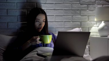 Asyalı kadın yatak odasında geç dizüstü bilgisayar üzerinde çalışan kahve içme, son tarih toplantı