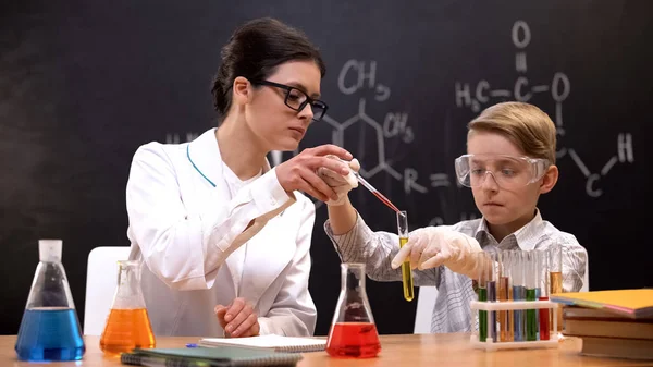 老师帮助小学生在试管 化学课上滴红物质 — 图库照片