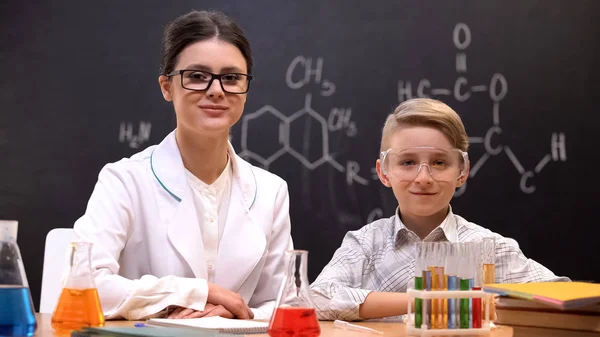 年轻的女化学老师和小学生看着相机和微笑 — 图库照片