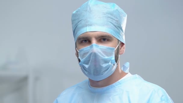 Cirurgião profissional olhando câmera decolando máscara protetora, salvando vidas — Vídeo de Stock