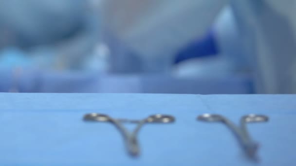 Tijeras quirúrgicas en la mesa, trabajador médico operando paciente, equipo del hospital — Vídeos de Stock