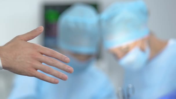 Enfermera ayudando al médico a poner guantes médicos antes de la operación, esterilidad hospitalaria — Vídeos de Stock