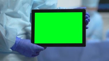 Yeşil ekran tablet tutan hastane çalışanı, sağlık sigortası uygulaması, klinik sitesi