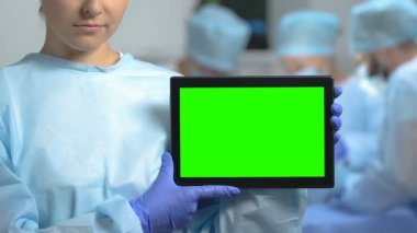 Yeşil ekran tablet gösteren tıbbi üniforma genç kadın, klinik uygulaması, sağlık