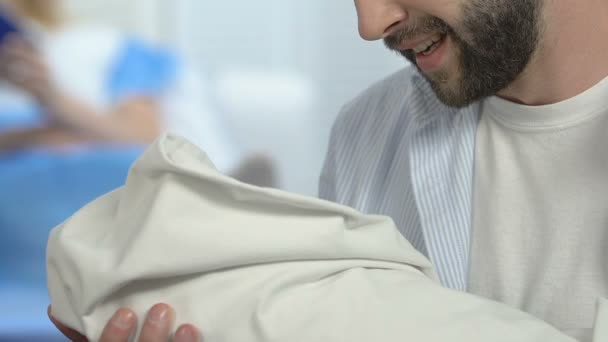 Sonriente padre sosteniendo recién nacido en el hospital mirando al bebé, la felicidad de la paternidad — Vídeos de Stock