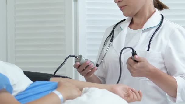 Enfermera del hospital que mide la presión arterial de la mujer embarazada en la cama, atención médica — Vídeo de stock
