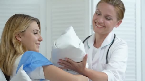 Glücklicher Arzt, der einer jungen Mutter im Bett ein Neugeborenes gibt, Gesundheitsfürsorge für die Mutterschaft — Stockvideo
