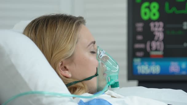 Пациентка с кислородной маской лежит на больничной койке, неотложная медицинская операция — стоковое видео