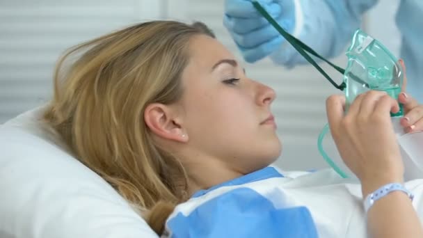 Pielęgniarka szpitalna pomaga chorej kobiecie założyć maskę tlenową, zaburzenia układu oddechowego — Wideo stockowe